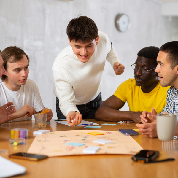Photo for illustrative purposes. Four people excitedly roll dice around a central table.